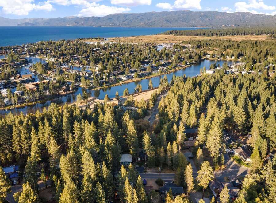 Experience the ultimate lakeside lifestyle with this stunning aerial view of a waterfront community nestled among tall pine trees.