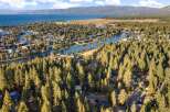 Experience the ultimate lakeside lifestyle with this stunning aerial view of a waterfront community nestled among tall pine trees.