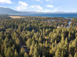 Experience the ultimate lakeside lifestyle with this stunning aerial view of a picturesque neighborhood nestled among towering pine trees.
