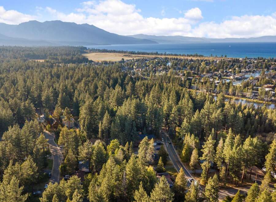 Experience the ultimate mountain lifestyle with this stunning aerial view of a lakeside community nestled amongst towering pine trees.