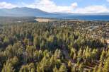 Experience the ultimate mountain lifestyle with this stunning aerial view of a lakeside community nestled amongst towering pine trees.