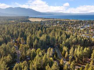 Experience the ultimate mountain lifestyle with this stunning aerial view of a lakeside community nestled amongst towering pine trees.