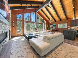 Experience breathtaking mountain living in this stunning home featuring a spacious open-concept living area with a soaring vaulted ceiling and exposed wood beams.
