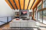 Experience modern living in this stunning great room, featuring a vaulted wood-paneled ceiling with exposed beams and a sleek stone fireplace.