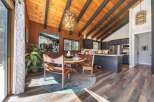 Experience rustic charm in this open-concept living space, featuring a vaulted wood-paneled ceiling with exposed beams and a striking modern chandelier.