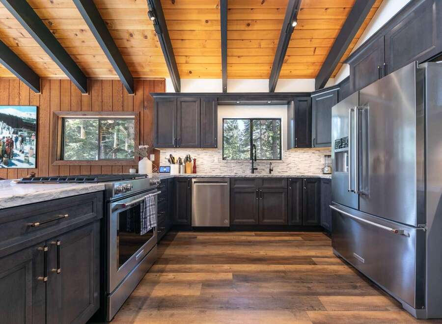 Experience rustic charm and modern convenience in this stunning kitchen, featuring dark wood cabinetry, a sleek stainless steel refrigerator, and a gas range perfect for culinary adventures.