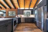 Experience rustic charm and modern convenience in this stunning kitchen, featuring dark wood cabinetry, a sleek stainless steel refrigerator, and a gas range perfect for culinary adventures.