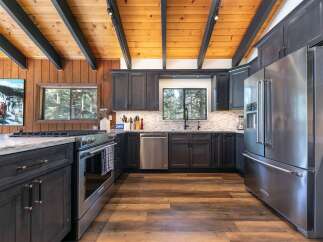 Experience rustic charm and modern convenience in this stunning kitchen, featuring dark wood cabinetry, a sleek stainless steel refrigerator, and a gas range perfect for culinary adventures.