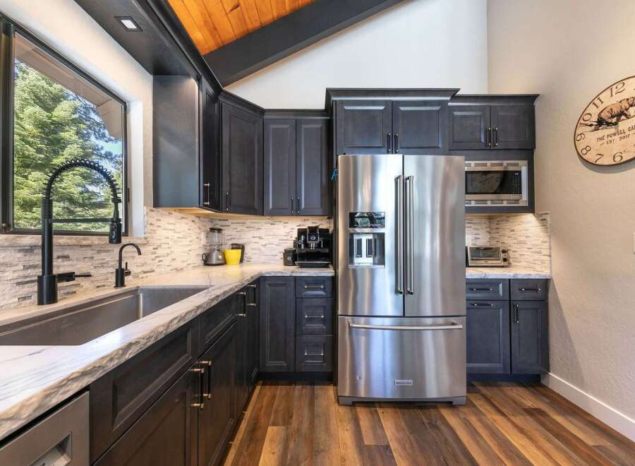 Experience modern living in this stunning kitchen featuring sleek dark cabinetry and a large stainless steel refrigerator.