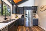 Experience modern living in this stunning kitchen featuring sleek dark cabinetry and a large stainless steel refrigerator.