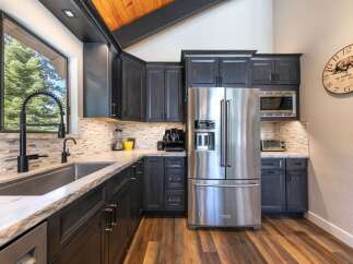 Experience modern living in this stunning kitchen featuring sleek dark cabinetry and a large stainless steel refrigerator.