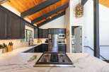 Experience modern mountain living in this stunning kitchen, featuring dark cabinetry, a sleek marble countertop, and a professional gas range.