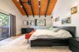 Experience rustic charm in this inviting bedroom featuring a vaulted wood-paneled ceiling with exposed beams and modern lighting.