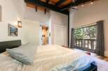 Experience serene living in this charming bedroom featuring a vaulted ceiling with exposed wood beams and a modern black fan.