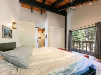 Experience serene living in this charming bedroom featuring a vaulted ceiling with exposed wood beams and a modern black fan.