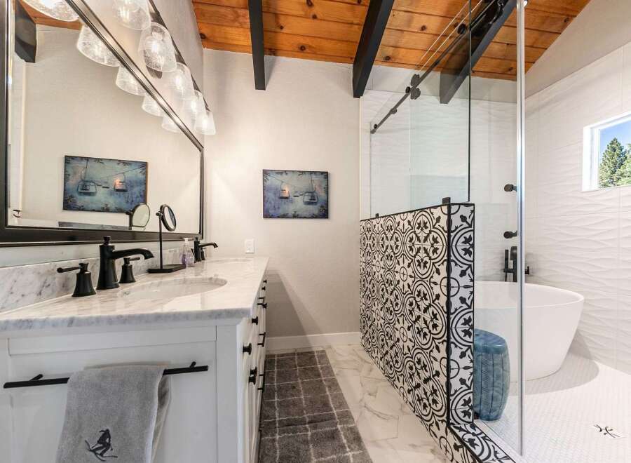 Experience luxury in this stunning bathroom featuring a freestanding tub and a modern glass-enclosed shower with intricate tile work.