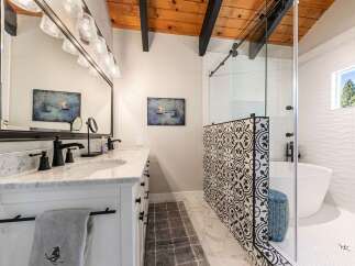 Experience luxury in this stunning bathroom featuring a freestanding tub and a modern glass-enclosed shower with intricate tile work.