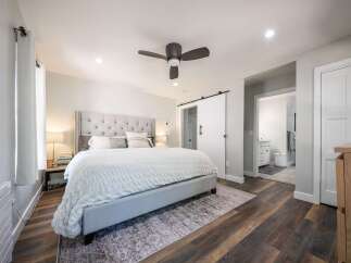 Experience luxury and comfort in this master bedroom, featuring a plush tufted headboard and a cozy white duvet.