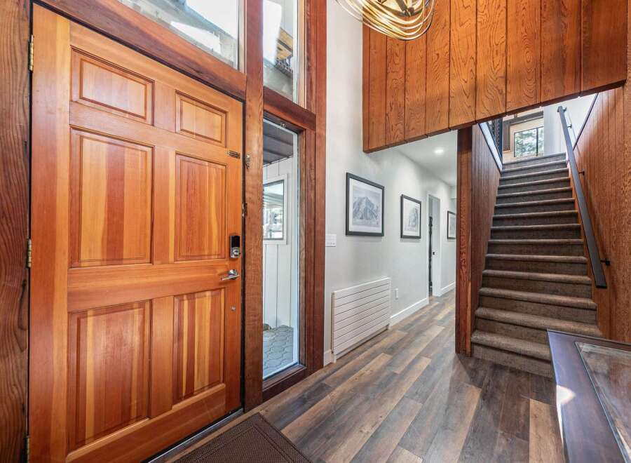 Step into a warm and inviting entryway featuring a stunning solid wood door and a grand staircase with plush carpeting.
