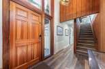 Step into a warm and inviting entryway featuring a stunning solid wood door and a grand staircase with plush carpeting.