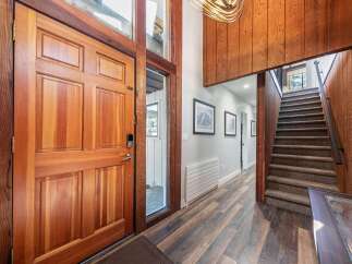 Step into a warm and inviting entryway featuring a stunning solid wood door and a grand staircase with plush carpeting.