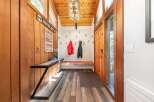 Step into a warm and inviting entryway featuring rustic wood paneling and a vaulted ceiling with a striking modern chandelier.