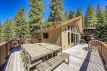 Enjoy outdoor living and dining on this expansive wooden deck, perfect for entertaining guests amidst a serene forest setting.