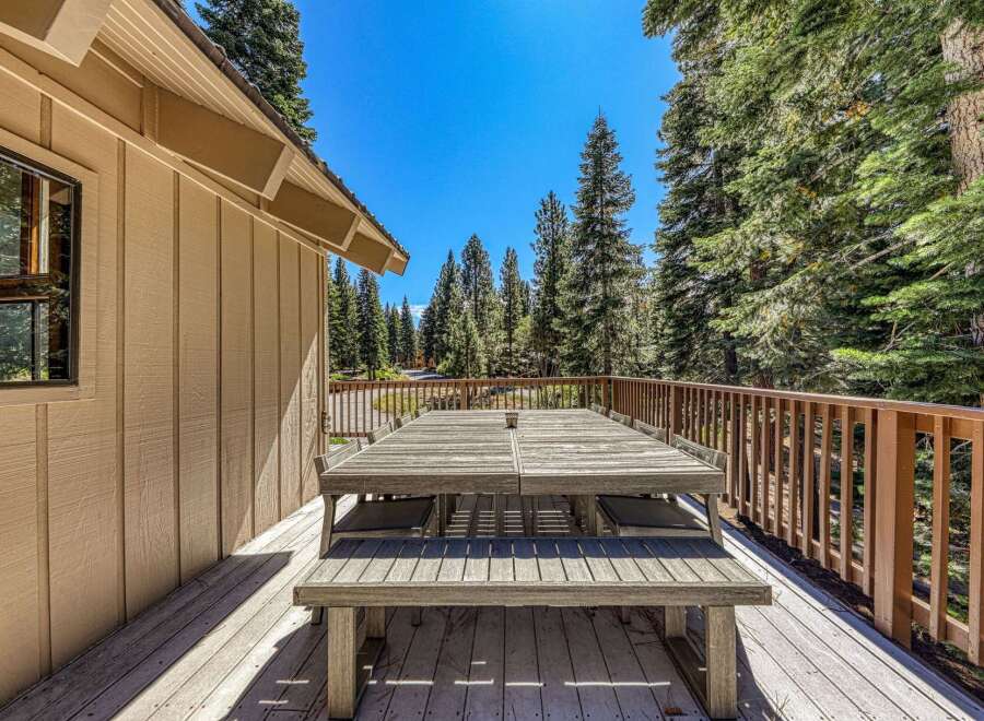 Enjoy al fresco dining on this spacious wooden deck, complete with a large picnic table and benches, perfect for gathering with loved ones.
