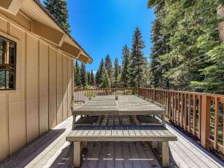 Enjoy al fresco dining on this spacious wooden deck, complete with a large picnic table and benches, perfect for gathering with loved ones.