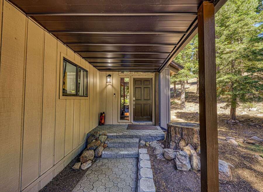 Welcome guests to this charming mountain retreat with a covered entryway featuring a dark wood door and a side window for natural light.
