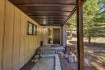 Welcome guests to this charming mountain retreat with a covered entryway featuring a dark wood door and a side window for natural light.