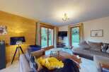 Experience cozy living in this charming mountain retreat, featuring a warm wood-paneled living room with comfortable seating and a large TV.