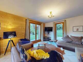 Experience cozy living in this charming mountain retreat, featuring a warm wood-paneled living room with comfortable seating and a large TV.