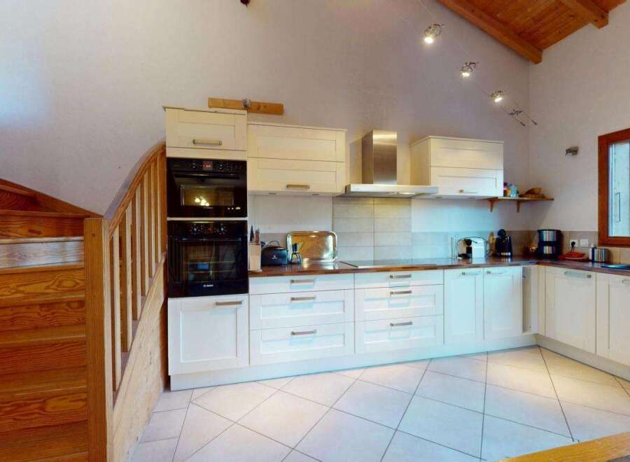 Discover this charming kitchen featuring a sleek stainless steel range hood and modern built-in ovens.
