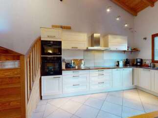 Discover this charming kitchen featuring a sleek stainless steel range hood and modern built-in ovens.
