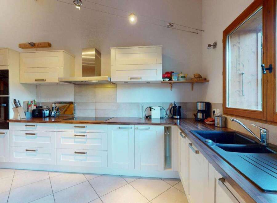 This spacious kitchen features modern white cabinetry and a sleek stainless steel range hood, perfect for any home chef.