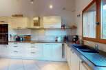 This spacious kitchen features modern white cabinetry and a sleek stainless steel range hood, perfect for any home chef.