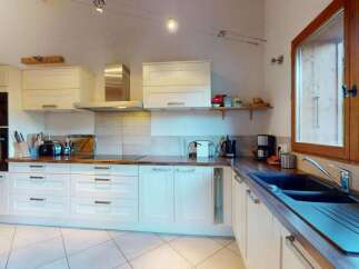 This spacious kitchen features modern white cabinetry and a sleek stainless steel range hood, perfect for any home chef.
