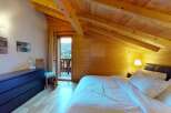 Experience cozy mountain living in this charming attic bedroom, featuring exposed wooden beams and a warm, inviting ambiance.