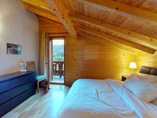 Experience cozy mountain living in this charming attic bedroom, featuring exposed wooden beams and a warm, inviting ambiance.