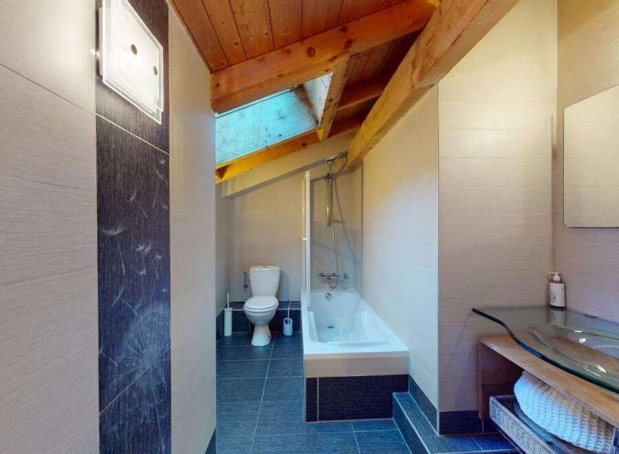 Discover this charming bathroom featuring a sleek glass vanity and a modern bathtub with a shower.