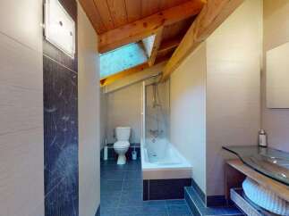 Discover this charming bathroom featuring a sleek glass vanity and a modern bathtub with a shower.