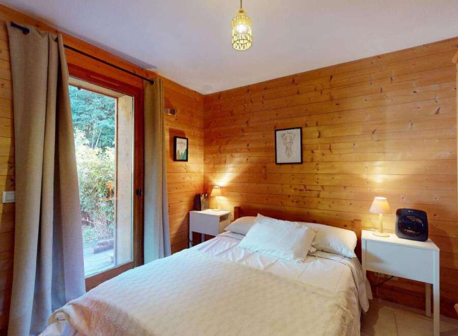 Experience rustic charm in this cozy wooden cabin bedroom, featuring a comfortable bed adorned with crisp white linens and plush pillows.