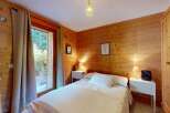 Experience rustic charm in this cozy wooden cabin bedroom, featuring a comfortable bed adorned with crisp white linens and plush pillows.