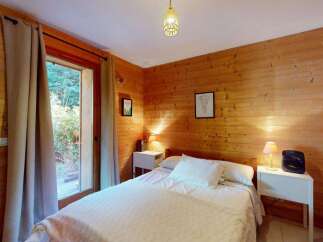 Experience rustic charm in this cozy wooden cabin bedroom, featuring a comfortable bed adorned with crisp white linens and plush pillows.