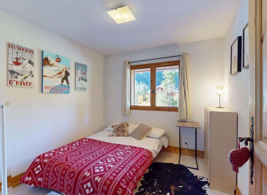 This charming bedroom features a cozy single bed adorned with a vibrant red and white patterned blanket, perfect for a restful night's sleep.