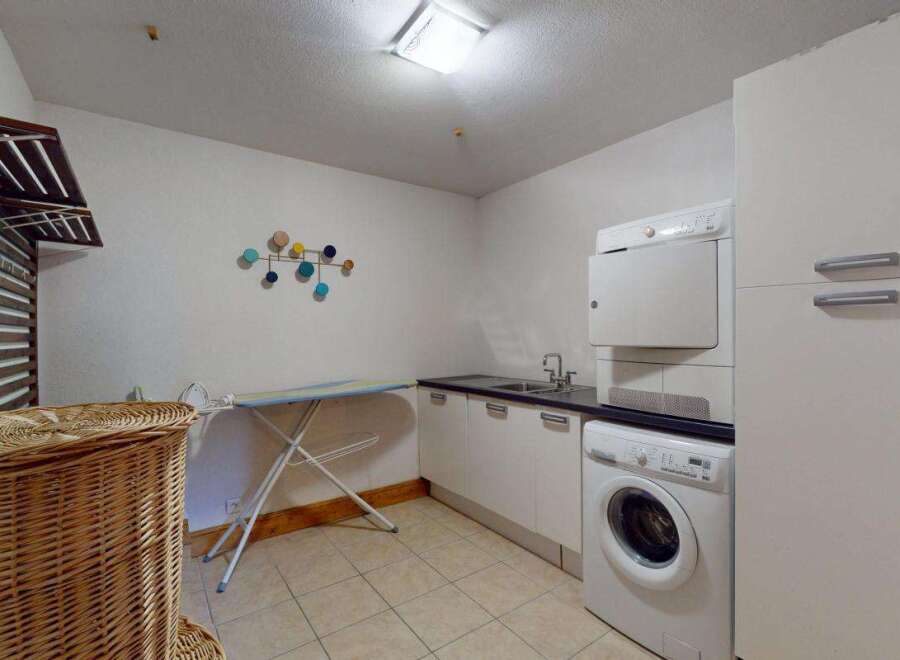 This laundry room offers ample space and functionality, featuring a stacked washer and dryer for efficient use of space.
