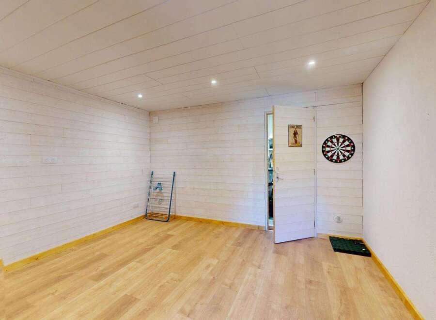 Step into this charming room, featuring a rustic wooden door and walls clad in light-toned wood paneling.