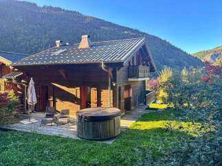 Experience serene mountain living in this charming wooden chalet, complete with a relaxing hot tub on the deck.