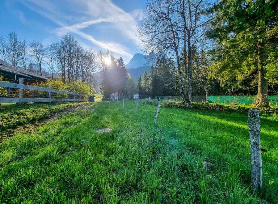 Experience serene living in this picturesque property, featuring a charming wooden fence and lush green meadows perfect for outdoor activities.